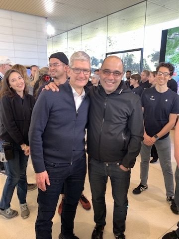 Tim Cook with his arm around Baha Cinar's shoulder, team members smiling behind them at Apple Park