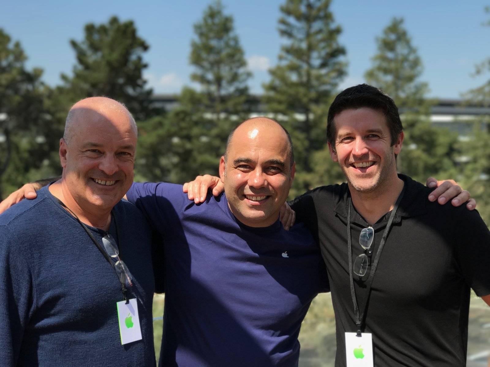 Baha Cinar at Apple Park with John Ternus and a colleague, the ring building visible behind the trees