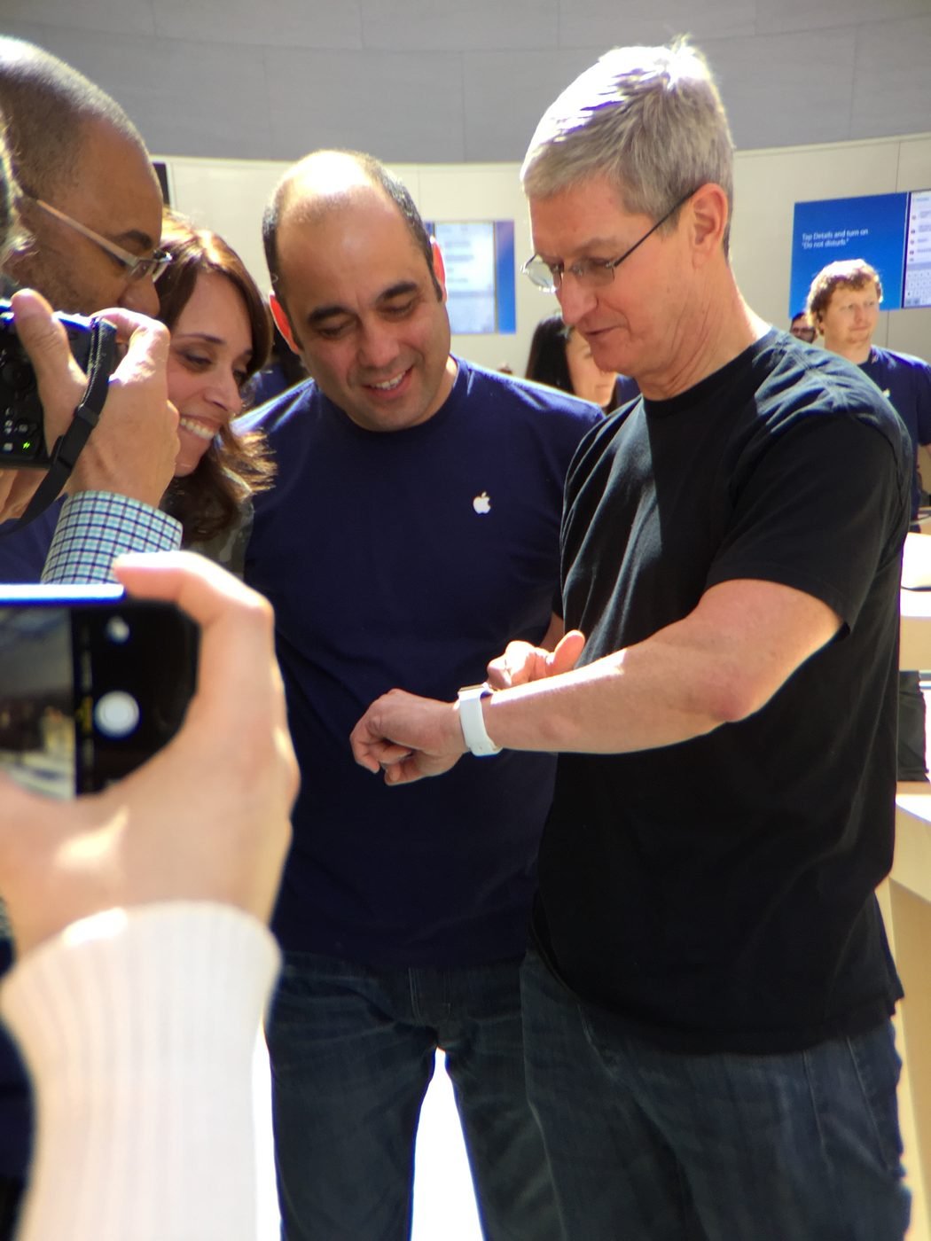 Tim Cook showing the Apple Watch on his wrist while Baha Cinar and colleagues look on, photographers crowding in